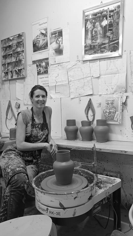 Ceramicist shaping a piece on the wheel in the studio
